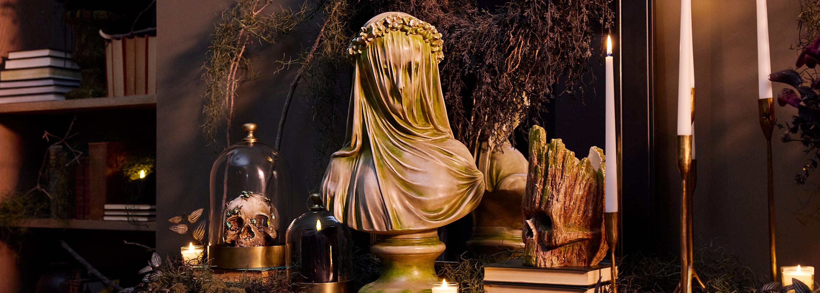 Grim Gardens Halloween decor with a draped bust, skull, candles, and moss