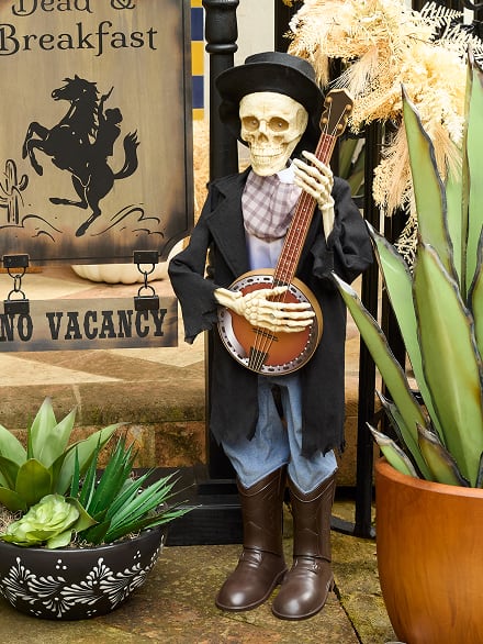 Skeleton animatronic dressed in a coat and hat holding a banjo