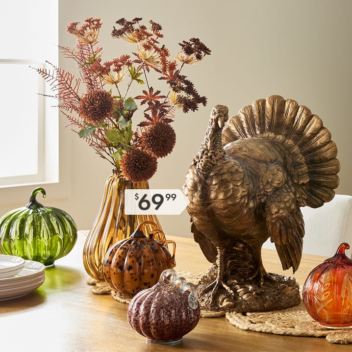 Bronze turkey statue with autumn flowers and colorful glass pumpkins