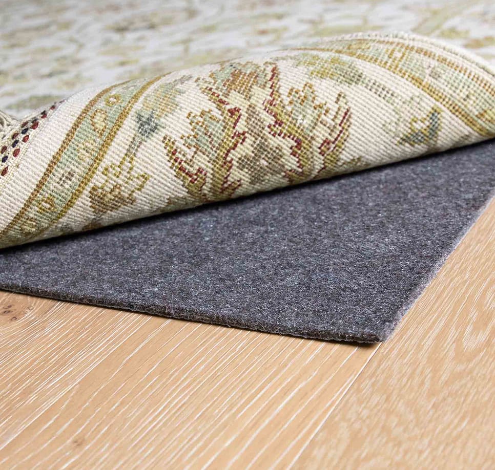 Area rug rolled back to show a protective rug pad underneath